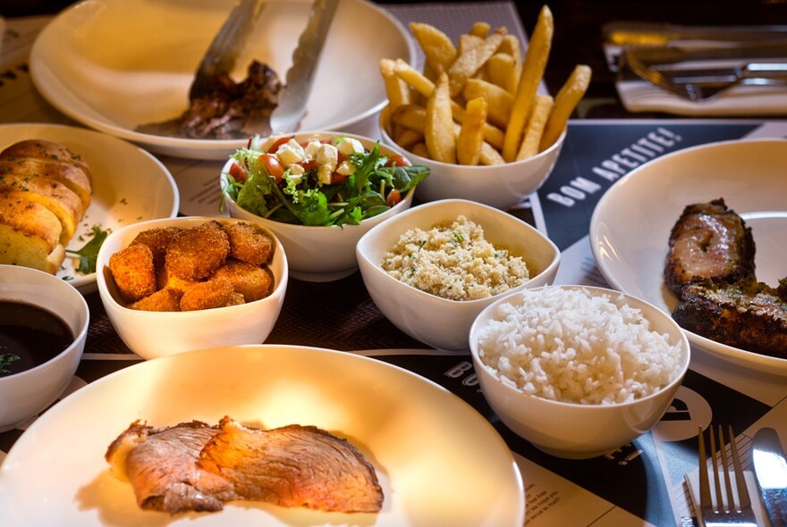 Array of dishes on a table including carved meat and vegetable side dishes.