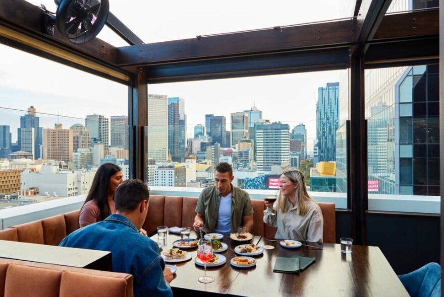 A group of four people drinking cocktails on a rooftop