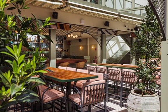 A rooftop with tables umbrellas and chairs.