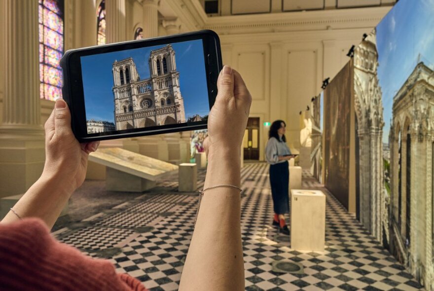 A museum patron using a HistoPad, an augmented reality device, to learn more about Notre Dame. 