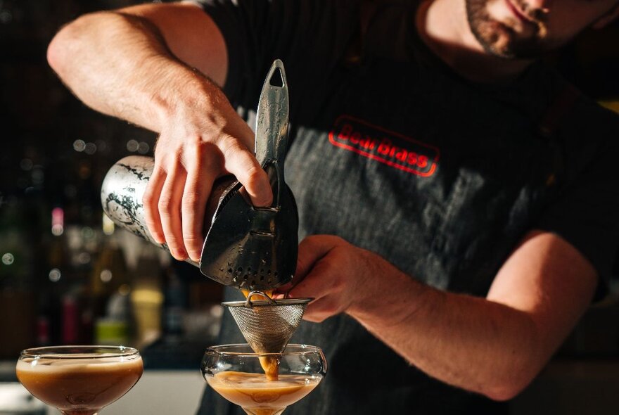 A bartender pouring a cocktail.