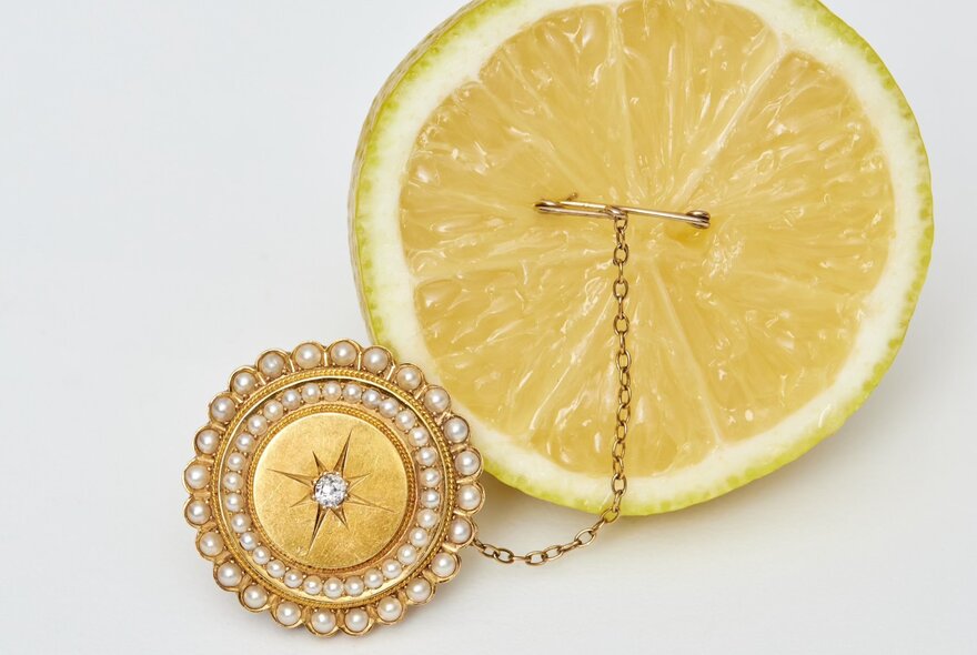Victorian round brooch with pearls attached to a sliced lemon.