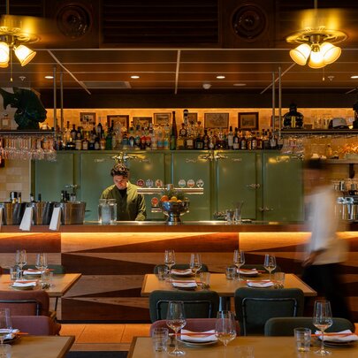 Restaurant dining tables and long bar with soft lighting.