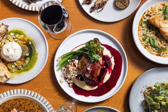 Array of Italian dishes on a table with a glass of wine.