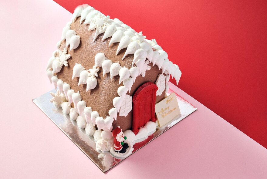 A decorated gingerbread house on a pink table.