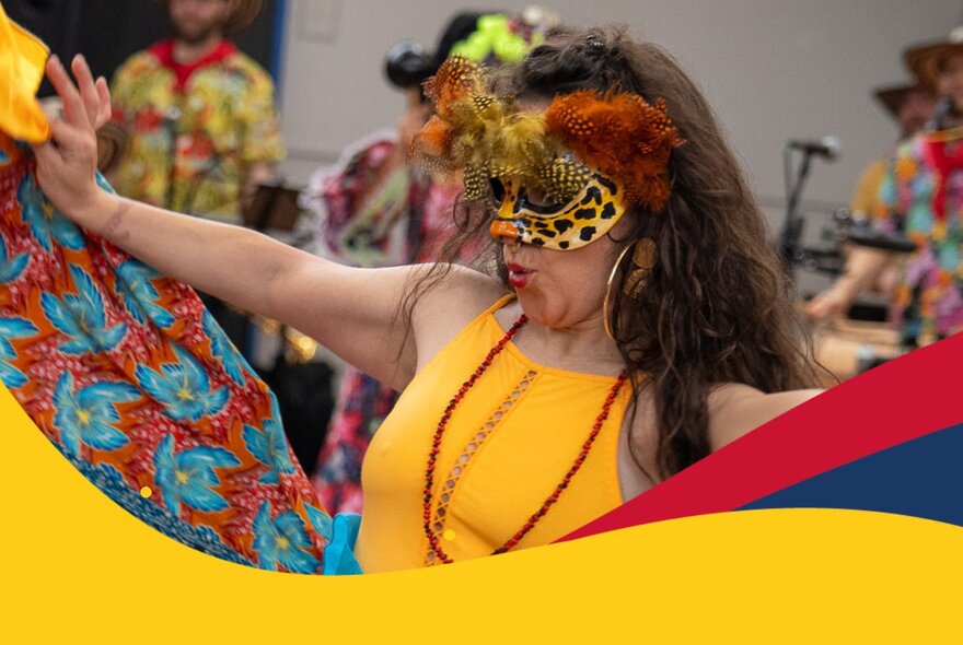A woman in a yellow dress wearing a yellow feathered masquerade mask.