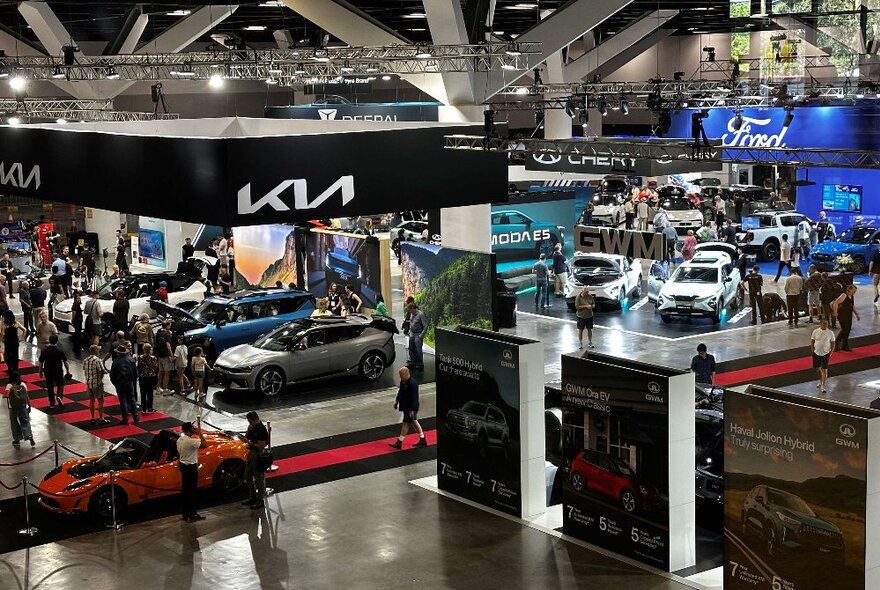 Showcase of electric vehicles in an expo setting with branded cars on display.