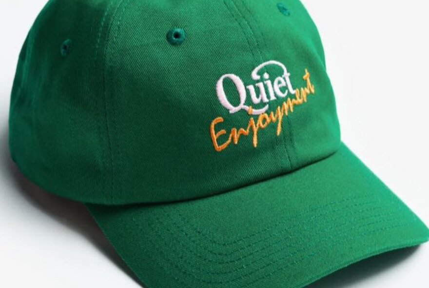 A green cap with the words quiet enjoyment embroidered on it