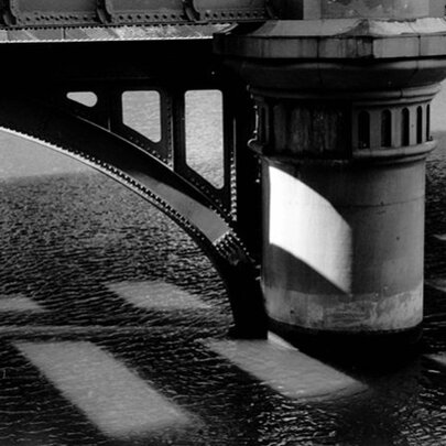 A black and white detail of a bridge pylon showing metal and stone construction. 