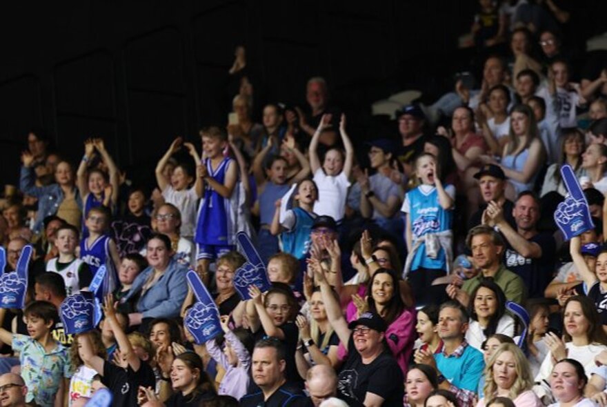 Sports fans seated and standing in tiered rows of seating.