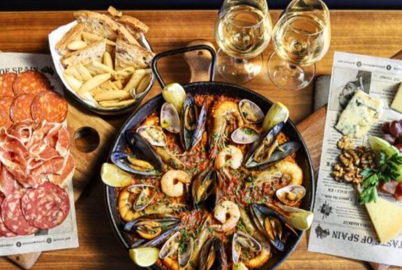 Looking down at platters of assorted tapas, and two glasses of wine.