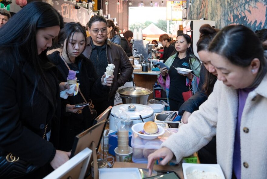 People queueing for food at an indoor market stall.