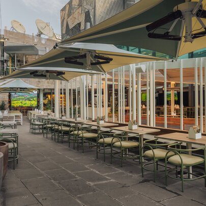 The outdoor seating area at Good Nature Hotel, showing table and chairs under large umbrellas.