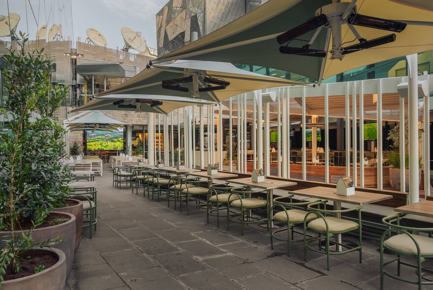 The outdoor seating area at Good Nature Hotel, showing table and chairs under large umbrellas.