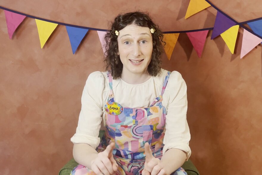 Children's entertainer seated under bunting.
