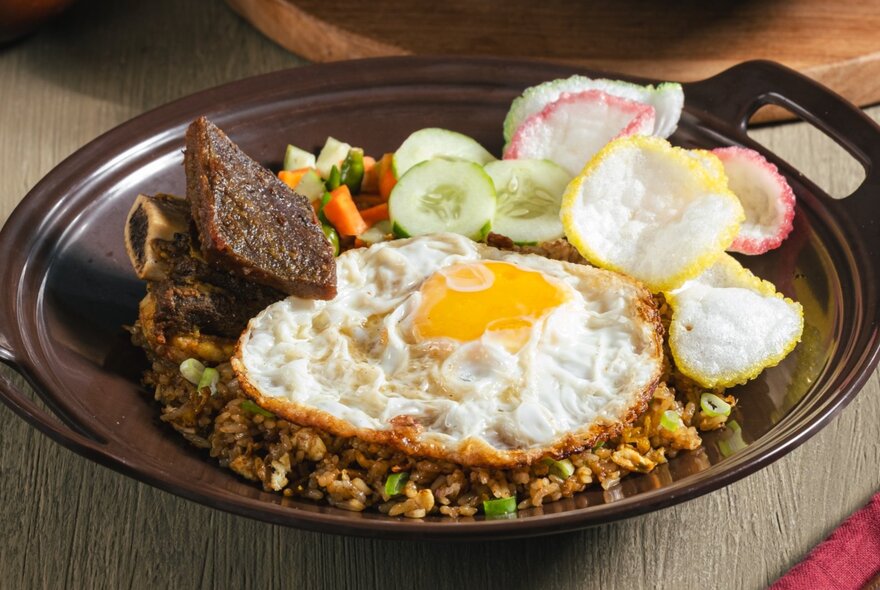 A plate of nasi goreng, a popular Indonesian fried rice dish served with a fried egg and condiments.
