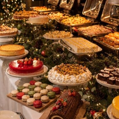 A generous high tea spread with full platters of savoury and sweet treats arranged on a long buffet table.