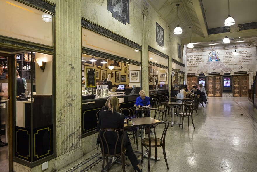 People seated outside a cafe in the art deco foyer of the Manchester Unity Building.