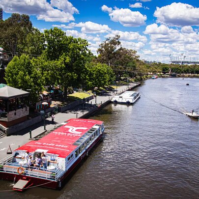 Aerial view of a river cruise boat with a red roof moored on the Yarra river. 