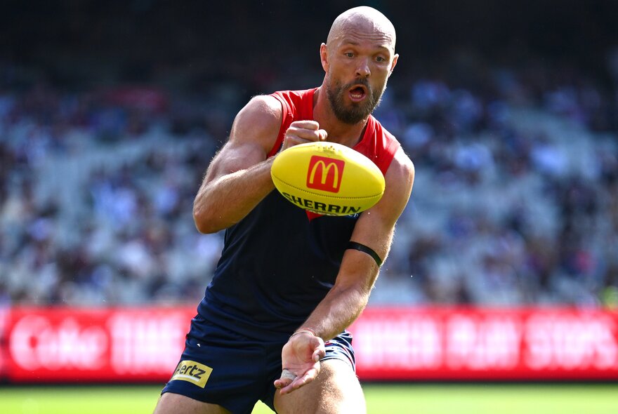 Melbourne AFL football player with a yellow ball during a match.