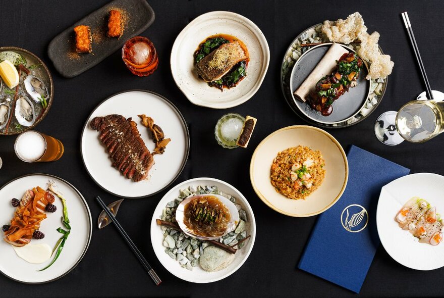 Overhead view of dark dining table set with an array of dishes and condiments.