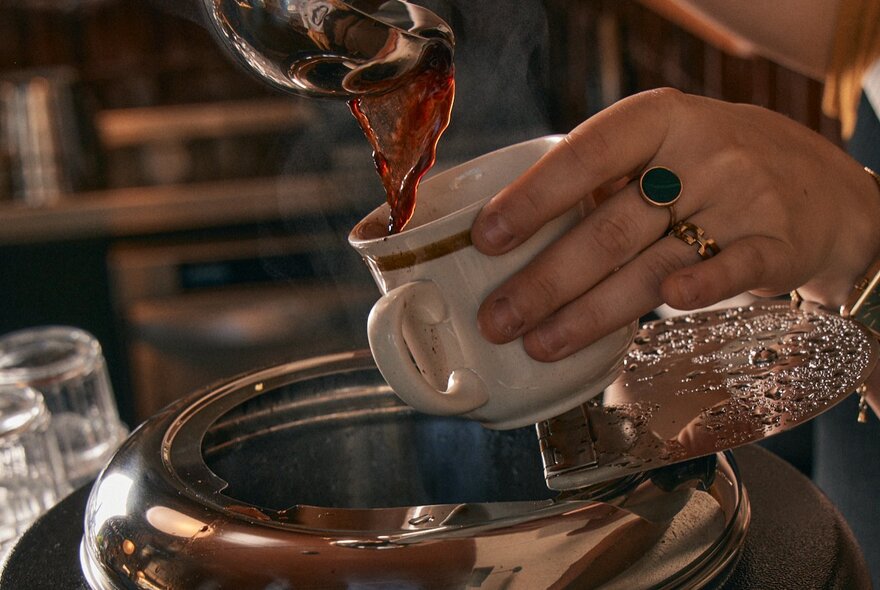 A hand pouting mulled wine into a cup.