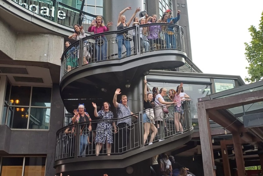 Group of disco walking tour participants dancing in the outside stairs of the shopping mall at Southgate.