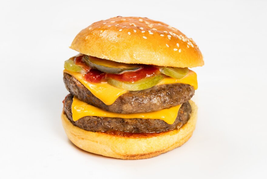 A double cheeseburger with two beef patties, sliced cheese, pickle and sauce in a bun. 