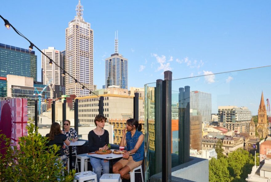 People sitting on a rooftop bar with city skyline views.