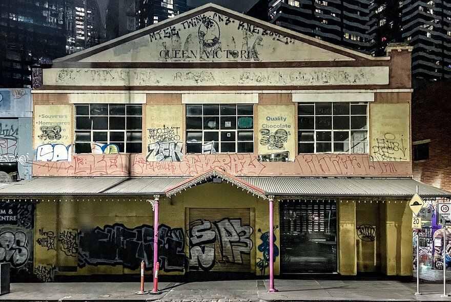 A decrepit old building with smashed windows covered in graffiti. 