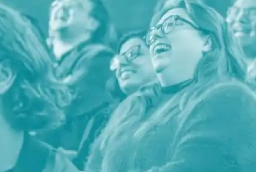People wearing spectacles seated in rows, laughing.