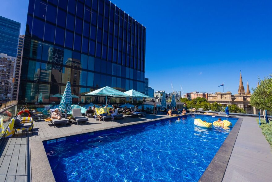 People lounging and swimming at a hotel rooftop pool.