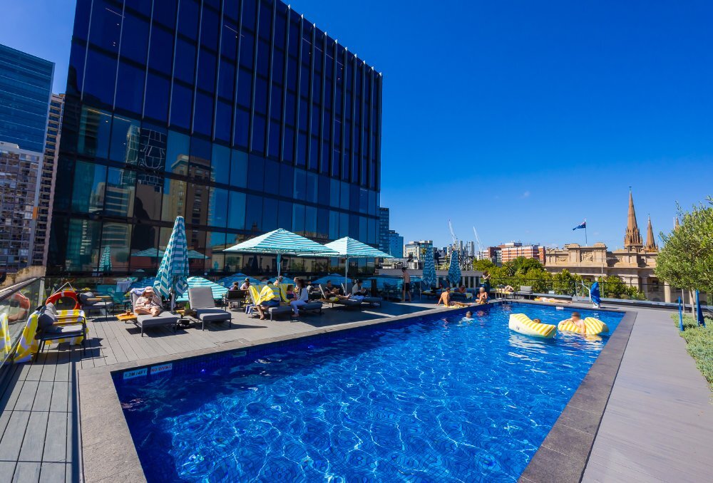 People lounging and swimming at a hotel rooftop pool.