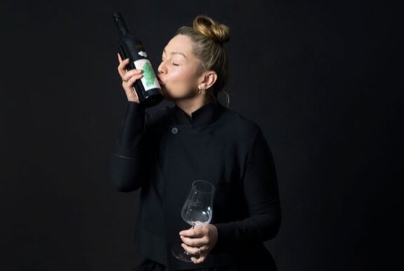 Winemaker Sarah Reed holding a bottle of wine to her face and kissing the label.