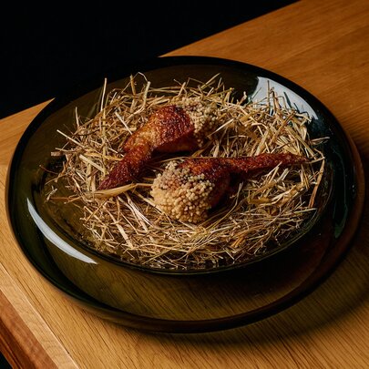 A fried chicken or poultry dish served on a bed of crispy straw or garnish, characteristic of fine-dining Japanese omakase courses.