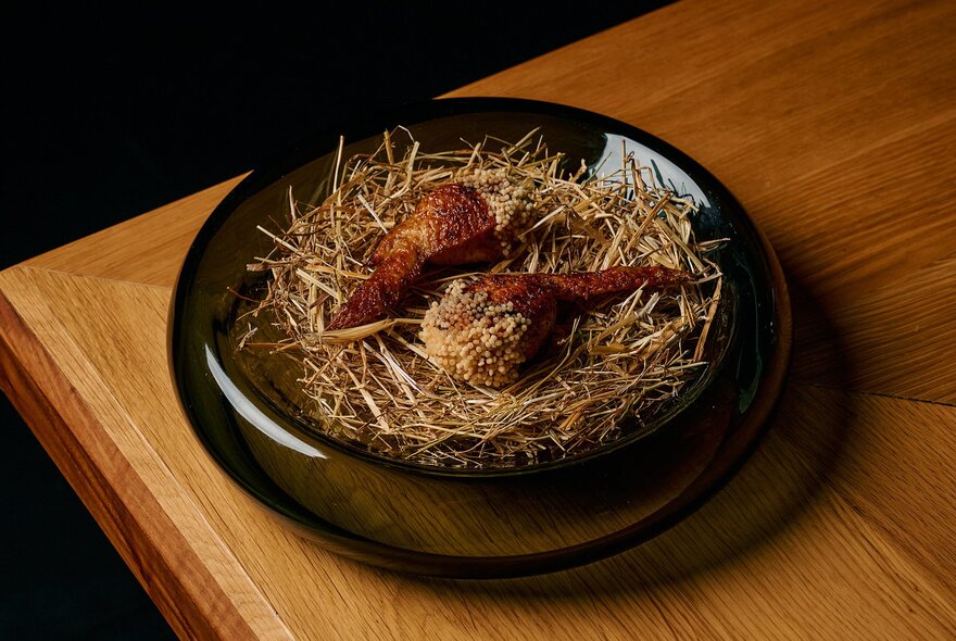 A fried chicken or poultry dish served on a bed of crispy straw or garnish, characteristic of fine-dining Japanese omakase courses.