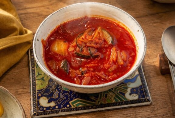 Bowl of spicy red chill soup on a table.