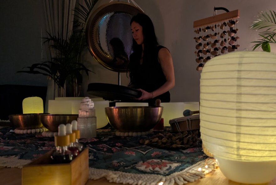 A person conducting a meditation exercise with cosmic gongs and vessels for sound resonance arranged on a Persian rug.