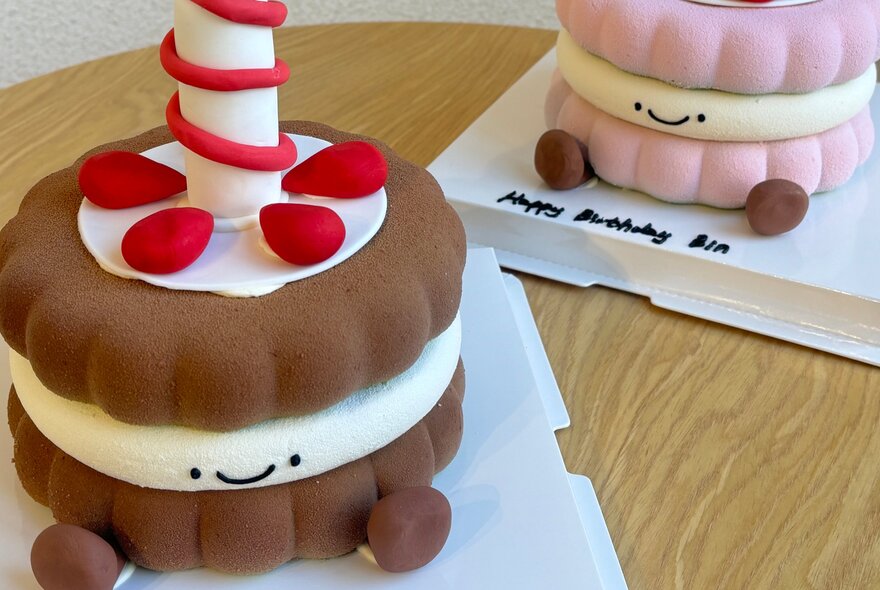 Jellycat cakes at Musu & Co, both with little faces and feet, one brown and one pink. 