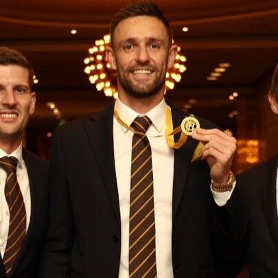 Three AFL footballers, one holding a medal around his neck.