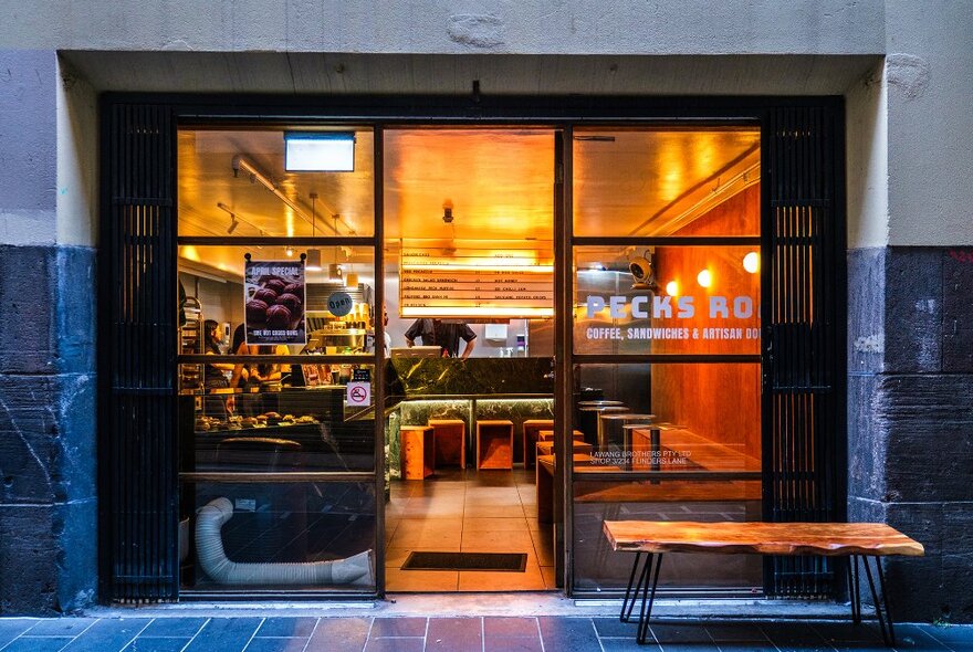 The warmly lit entrance to a small cafe with seating.