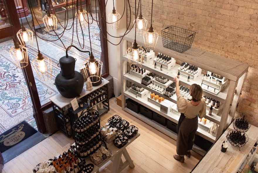 View of a perfume store from above with pendant lighting and a woman shopping 