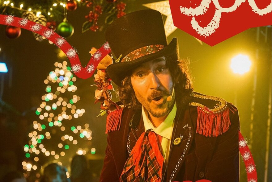 A man in a top hat and circus ringmaster style jacket singing in front of Christmas decorations.