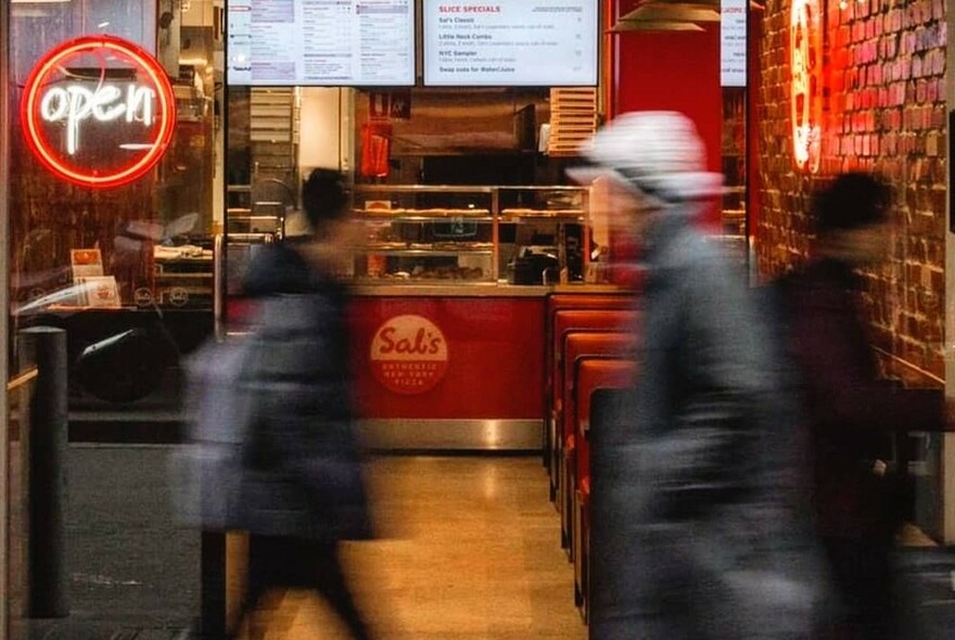 Blurred people passing the restaurant exterior.