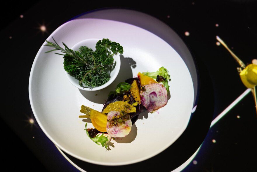 Dramatically plated dish of intricately arranged food with garnish.