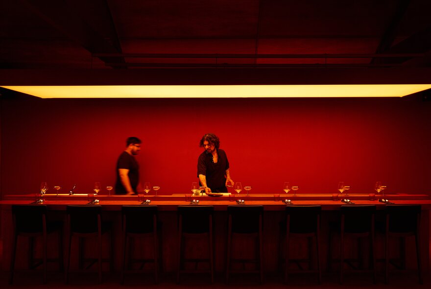 People behind a counter and red wall.