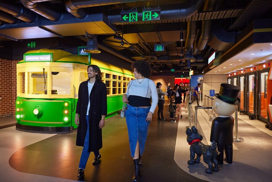 Two friends walking past a model of a tram. 