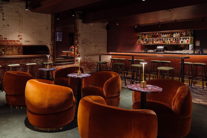 A dimly lit bar with velvet orange couches.