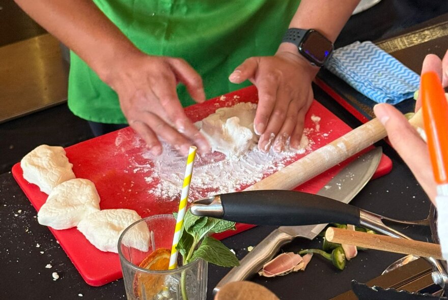 Hands working dough on a work surface during a Thai cooking workshop.