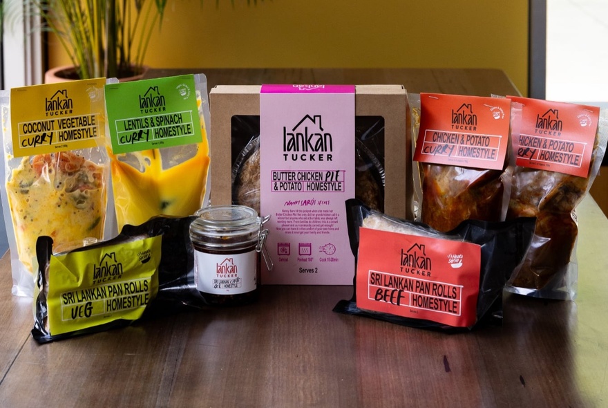 A selection of take-home Sri Lankan food products from Lankan Tucker, displayed on a wooden table.